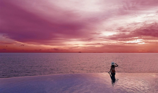 Woman in infinity pool at sunset